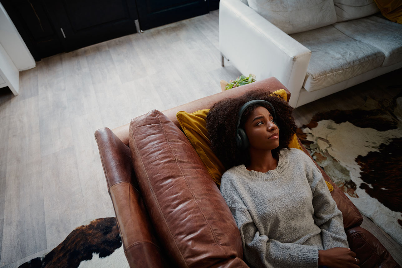 Sad woman lying on the couch with headphones