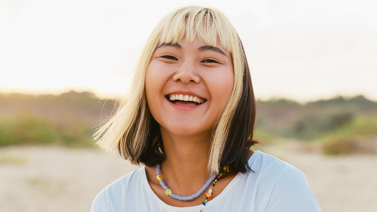 Young asian woman laughing while walking on beach