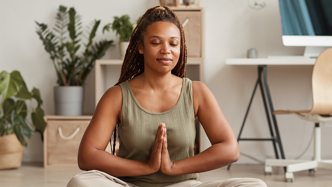 Young woman sitting in lotus position and meditating