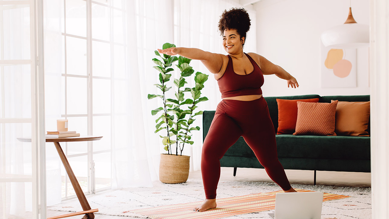 Healthy woman exercising at home watching online video on laptop