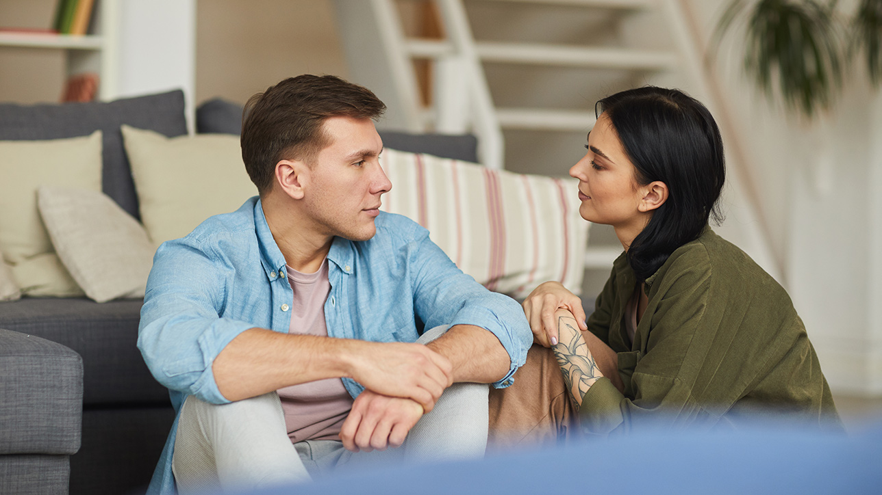 Young couple talking to each other sincerely while sitting on the floor
