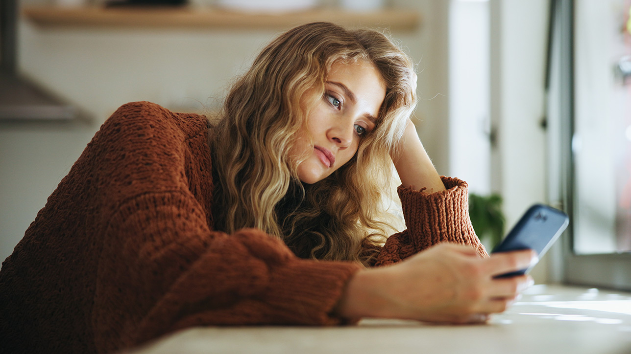 Woman sadly looking at her phone